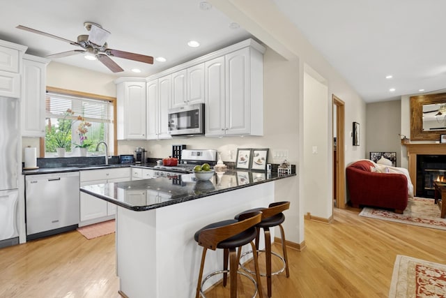 5055 N California Ave Unit 1S, Chicago, IL 60625 - kitchen with stainless steel appliances, a ceiling fan, light wood-style floors, white cabinetry, and recessed lighting