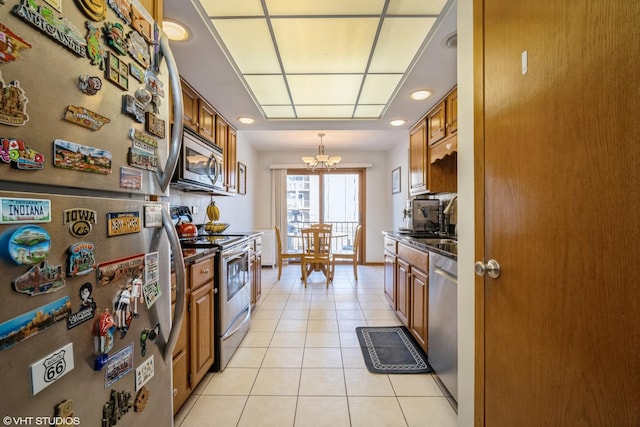 1380 Oakwood Ave Unit 306, Des Plaines, IL 60016 - kitchen with appliances with stainless steel finishes, brown cabinetry, dark countertops, a chandelier, and light tile patterned floors