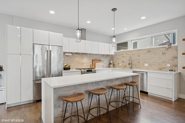 1633 N Saint Louis Ave, Chicago, IL 60647 - kitchen with stainless steel appliances, white cabinetry, a kitchen breakfast bar, backsplash, and recessed lighting