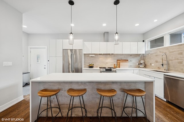 1633 N Saint Louis Ave, Chicago, IL 60647 - kitchen with stainless steel appliances, backsplash, white cabinets, a kitchen bar, and a kitchen island