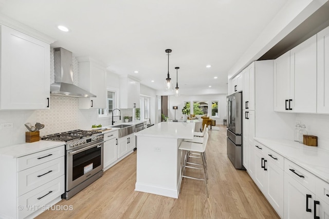 920 Hayes Ave, Oak Park, IL 60302 - kitchen with appliances with stainless steel finishes, wall chimney range hood, a kitchen bar, a center island, and white cabinets