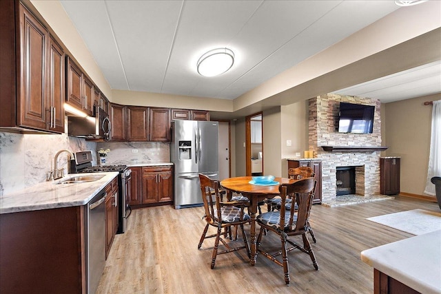 15031 Mayo Dr Unit 19D, Orland Park, IL 60462 - kitchen with stainless steel appliances, a sink, light wood-type flooring, tasteful backsplash, and a fireplace