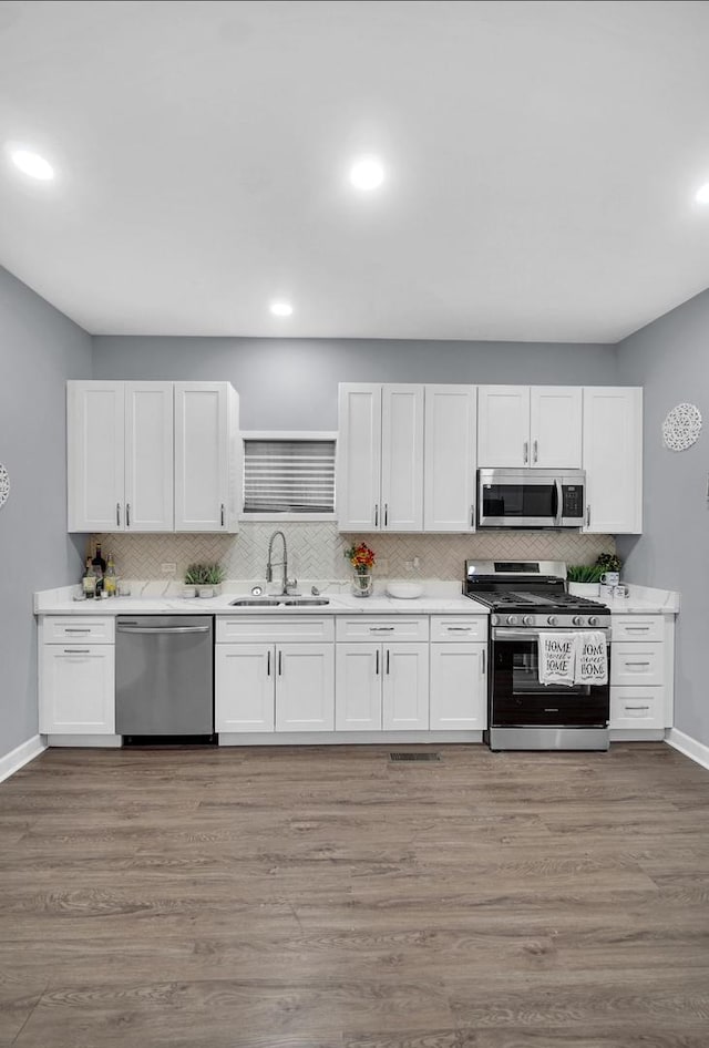 7825 S St Lawrence Ave, Chicago, IL 60619 - kitchen featuring appliances with stainless steel finishes, white cabinets, tasteful backsplash, light countertops, and recessed lighting
