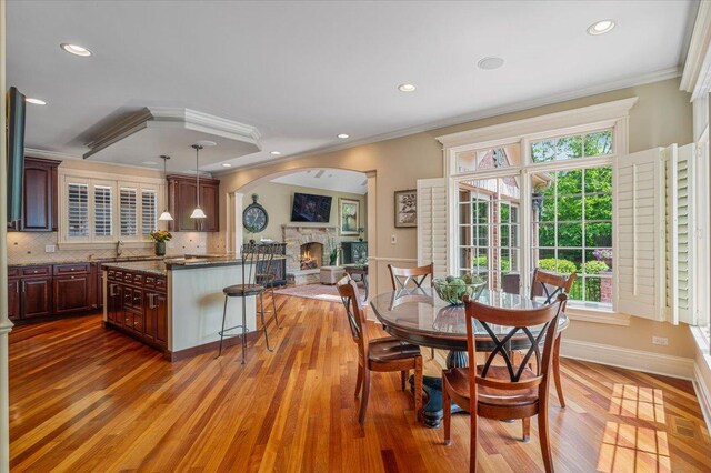 320 Vista Dr, Wilmette, IL 60091 - dining space with a fireplace, ornamental molding, light wood-style floors, healthy amount of natural light, and arched walkways