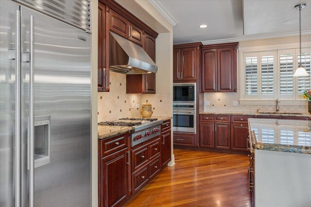 320 Vista Dr, Wilmette, IL 60091 - kitchen with stainless steel appliances, under cabinet range hood, dark wood-type flooring, crown molding, and light stone counters