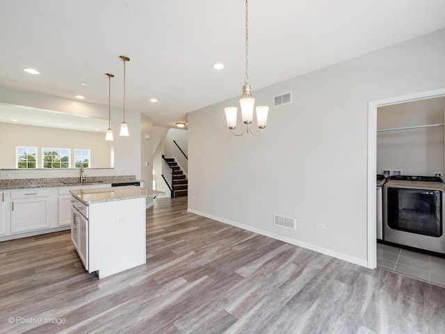 14017 S Belmont Dr, Homer Glen, IL 60491 - kitchen featuring washer / dryer, light wood-style flooring, white cabinetry, a chandelier, and a center island