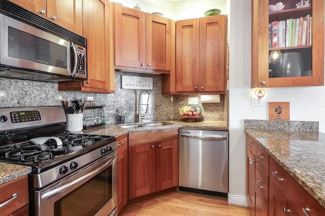 1355 W Washington Blvd Unit 4A, Chicago, IL 60607 - kitchen with stainless steel appliances, light wood-style flooring, backsplash, stone countertops, and brown cabinets