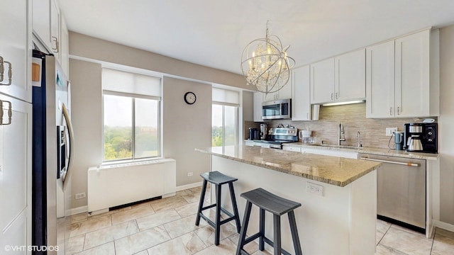 6833 N Kedzie Ave Unit 716, Chicago, IL 60645 - kitchen featuring appliances with stainless steel finishes, a chandelier, decorative backsplash, white cabinets, and a kitchen breakfast bar