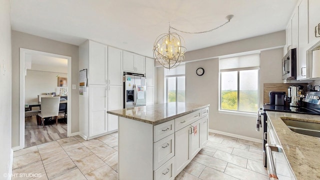 6833 N Kedzie Ave Unit 716, Chicago, IL 60645 - kitchen with appliances with stainless steel finishes, a kitchen island, light stone countertops, and a chandelier
