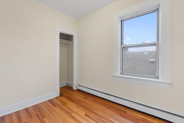 3357 S Oakley Ave, Chicago, IL 60608 - unfurnished bedroom featuring baseboard heating, light wood finished floors, baseboards, and a closet