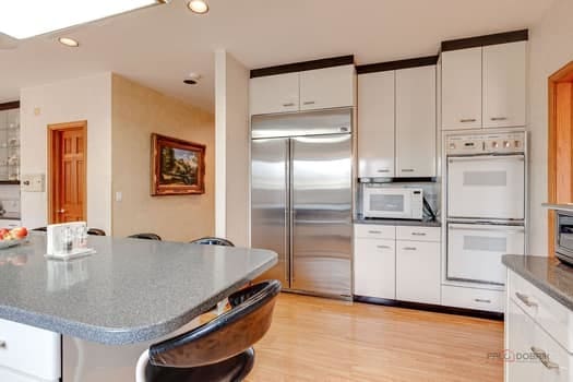 kitchen featuring white appliances, white cabinetry, recessed lighting, light wood finished floors, and a kitchen bar