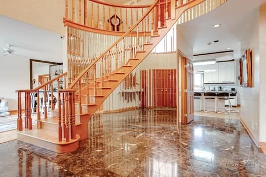 stairway featuring a high ceiling, marble tiled flooring, and baseboards