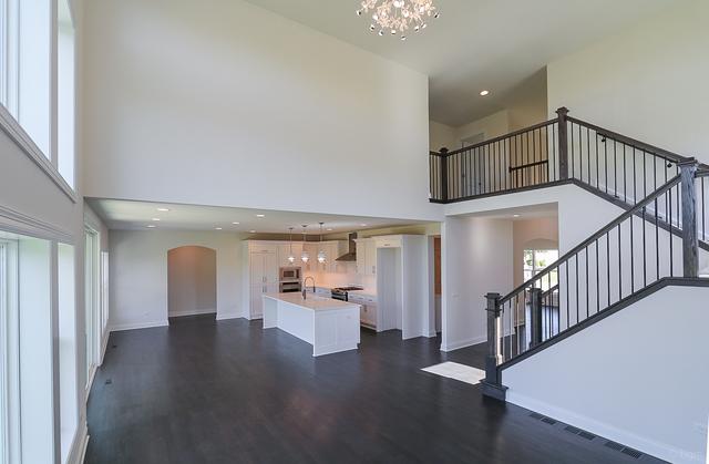 26101 W Forrester Dr, Plainfield, IL 60585 - unfurnished living room with arched walkways, a towering ceiling, dark wood finished floors, a sink, and a chandelier