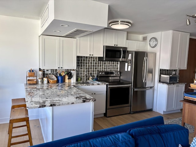 21 W Goethe St Unit 18D, Chicago, IL 60610 - kitchen featuring stainless steel appliances, light wood finished floors, white cabinets, and tasteful backsplash