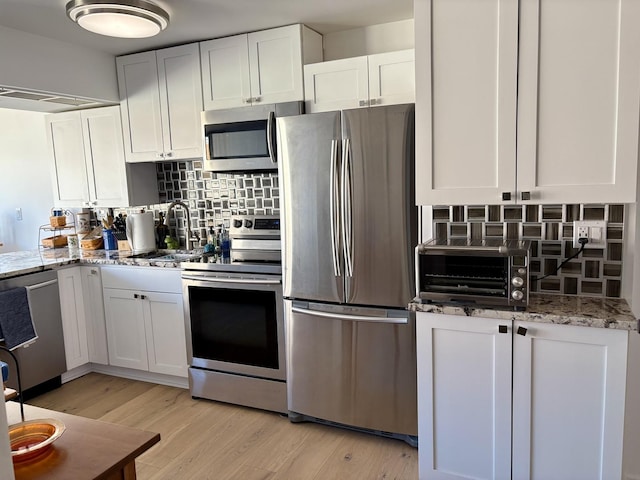 21 W Goethe St Unit 18D, Chicago, IL 60610 - kitchen with appliances with stainless steel finishes, backsplash, white cabinetry, and light stone countertops