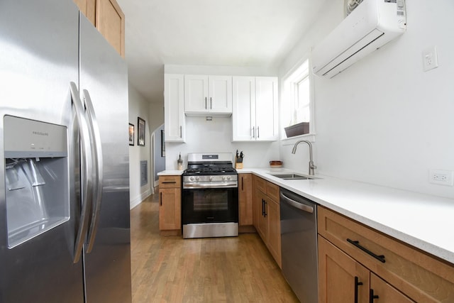 kitchen featuring stainless steel appliances, a wall unit AC, light wood-type flooring, light countertops, and white cabinetry