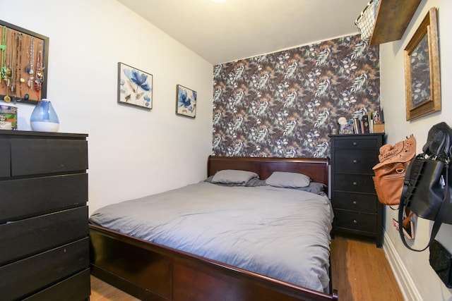 bedroom with wallpapered walls and wood finished floors