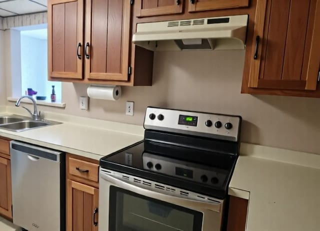 1503 Woodbridge Rd Unit 1F, Joliet, IL 60436 - kitchen with appliances with stainless steel finishes, under cabinet range hood, a sink, light countertops, and brown cabinetry