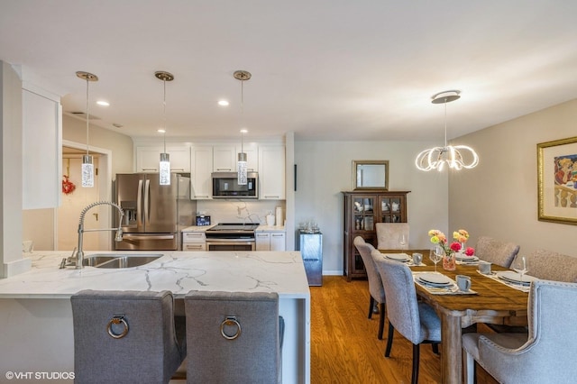 2 The Court Of Harborside Unit 209, Northbrook, IL 60062 - kitchen with appliances with stainless steel finishes, light wood finished floors, white cabinetry, a peninsula, and light stone countertops