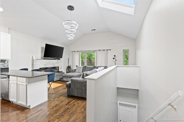 1457 E 71st Pl Unit 3, Chicago, IL 60619 - living room with dark wood-style flooring, vaulted ceiling, a skylight, a tiled fireplace, and a chandelier