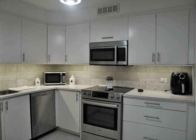 6007 N Sheridan Rd Unit 38G, Chicago, IL 60660 - kitchen with stainless steel appliances, white cabinetry, and decorative backsplash