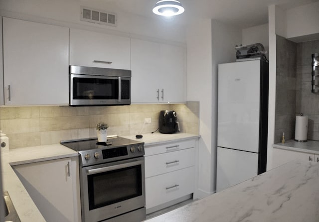 6007 N Sheridan Rd Unit 38G, Chicago, IL 60660 - kitchen featuring appliances with stainless steel finishes, white cabinetry, decorative backsplash, and light stone counters