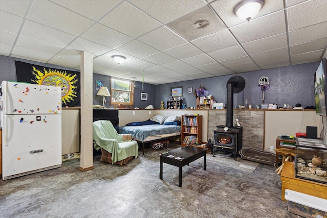 14710 Keslinger Rd, Dekalb, IL 60115 - bedroom with freestanding refrigerator, a drop ceiling, a wood stove, unfinished concrete flooring, and a textured wall