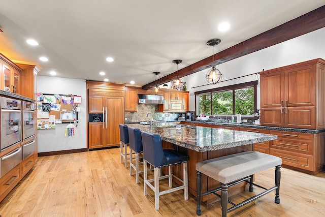 2500 Wahoo Ct, Morris, IL 60450 - kitchen featuring paneled refrigerator, under cabinet range hood, a breakfast bar area, decorative backsplash, and recessed lighting