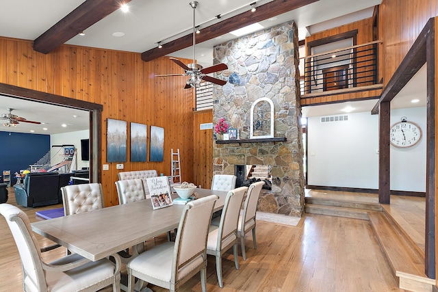 2500 Wahoo Ct, Morris, IL 60450 - dining area featuring ceiling fan, beamed ceiling, a fireplace, wooden walls, and light wood-style floors