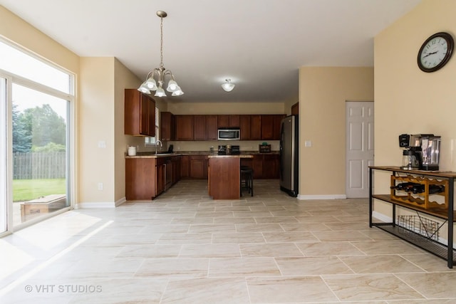 2210 Surrey St, Sycamore, IL 60178 - kitchen with stainless steel appliances, a chandelier, hanging light fixtures, a kitchen island, and a kitchen breakfast bar