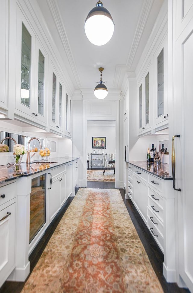 2123 N Bissell St, Chicago, IL 60614 - bar featuring crown molding, dark wood-type flooring, wine cooler, pendant lighting, and a sink