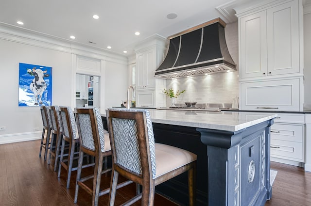2123 N Bissell St, Chicago, IL 60614 - kitchen with wall chimney exhaust hood, a large island with sink, tasteful backsplash, baseboards, and dark wood-type flooring