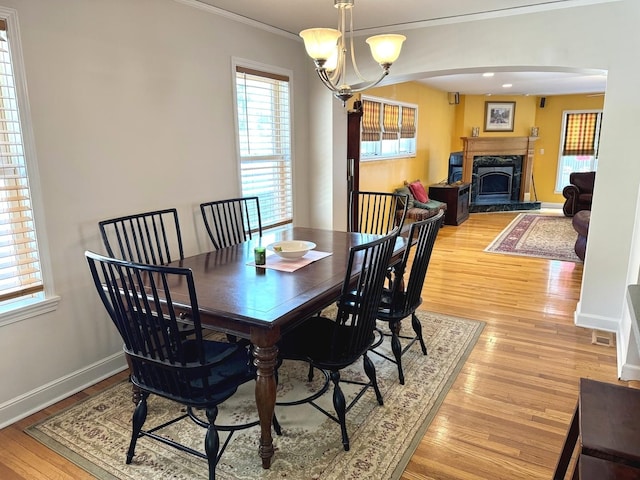 10043 S Artesian Ave, Chicago, IL 60655 - dining room with ornamental molding, light wood-type flooring, arched walkways, a fireplace with raised hearth, and a chandelier
