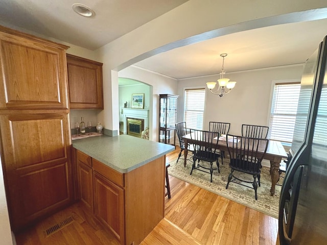 10043 S Artesian Ave, Chicago, IL 60655 - kitchen with freestanding refrigerator, brown cabinets, light wood-type flooring, arched walkways, and ornamental molding