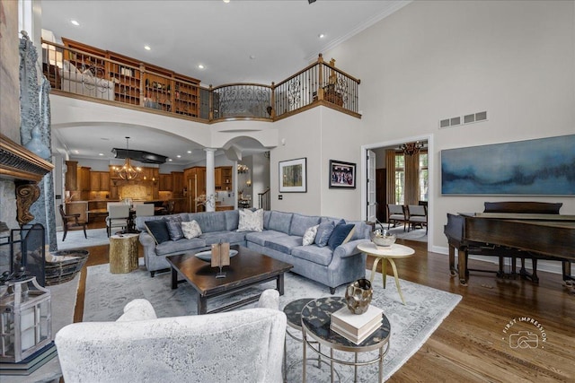 1088 Dunstan Rd, Geneva, IL 60134 - living room featuring decorative columns, a chandelier, wood finished floors, a towering ceiling, and ornamental molding