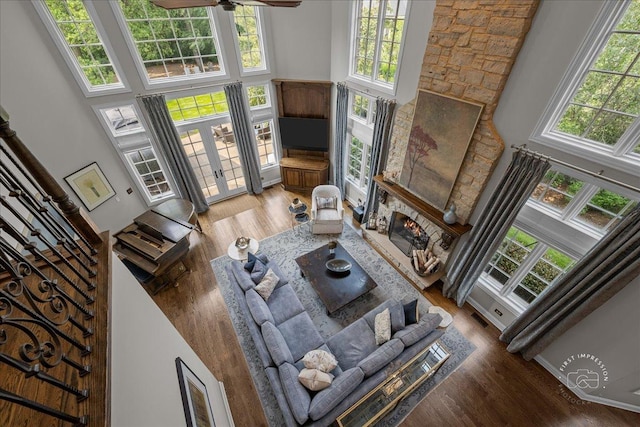 1088 Dunstan Rd, Geneva, IL 60134 - living room featuring a towering ceiling, a lit fireplace, wood finished floors, a ceiling fan, and french doors
