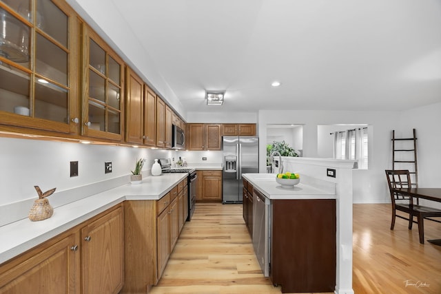 1910 Baldwin Way, Bolingbrook, IL 60490 - kitchen featuring appliances with stainless steel finishes, light wood finished floors, light countertops, brown cabinets, and glass insert cabinets