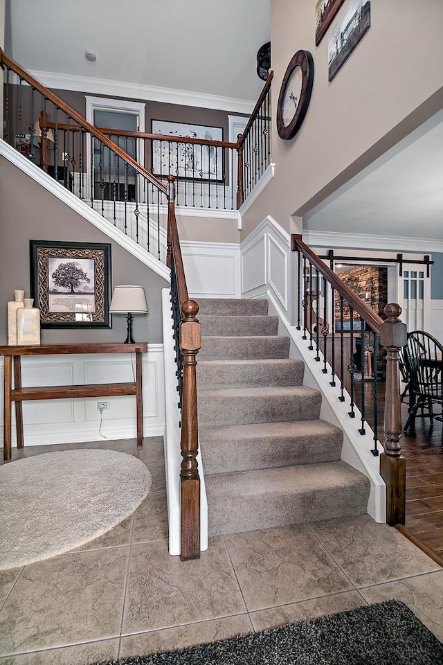 24450 Shawnee Ln, Manhattan, IL 60442 - staircase with crown molding, a towering ceiling, a decorative wall, and wainscoting