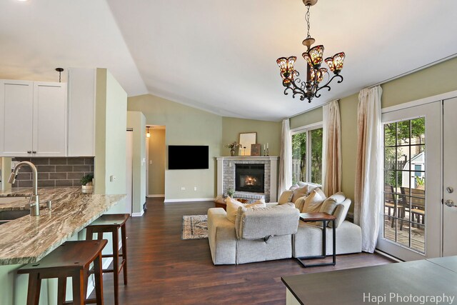 4008 W Lillian St, Mchenry, IL 60050 - living area featuring lofted ceiling, dark wood-style flooring, a fireplace, and a chandelier