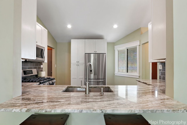 4008 W Lillian St, Mchenry, IL 60050 - kitchen with appliances with stainless steel finishes, a peninsula, vaulted ceiling, decorative backsplash, and light stone countertops