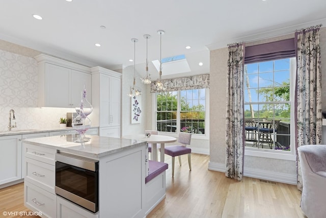 37 Harborside Way, Hawthorn Woods, IL 60047 - kitchen with stainless steel microwave, light wood finished floors, white cabinetry, light stone countertops, and a skylight