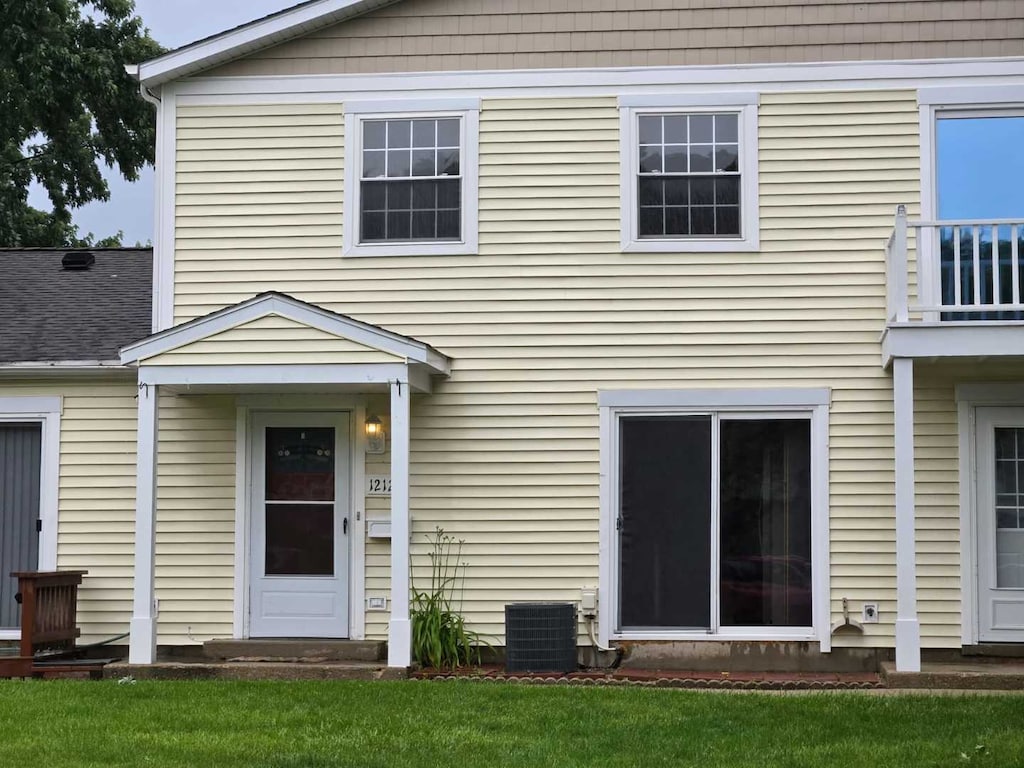 back of property with central AC and a lawn