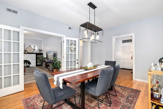 2127 W Pierce Ave Unit 2A, Chicago, IL 60622 - dining space featuring light wood-style flooring, french doors, a fireplace, and a chandelier