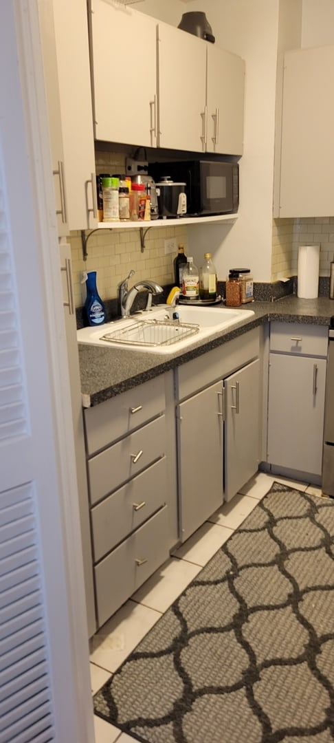 21 W Goethe St Unit 7C, Chicago, IL 60610 - kitchen featuring tasteful backsplash, a sink, white cabinets, and light tile patterned floors