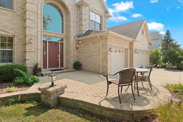 13613 Arborview Blvd, Plainfield, IL 60585 - doorway to property featuring brick siding, a garage, roof with shingles, and driveway