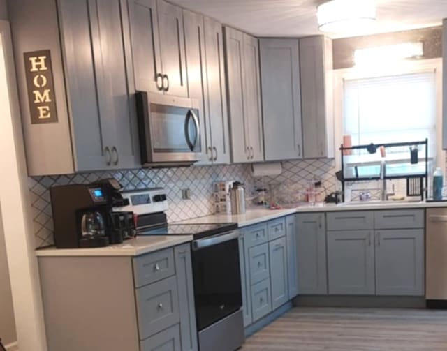 348 Niagara St, Park Forest, IL 60466 - kitchen featuring stainless steel appliances, gray cabinetry, light countertops, and decorative backsplash