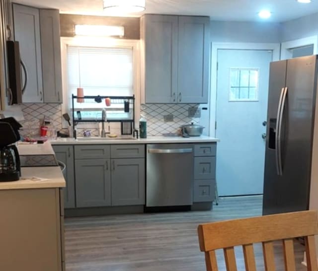 348 Niagara St, Park Forest, IL 60466 - kitchen featuring appliances with stainless steel finishes, light wood-style floors, tasteful backsplash, and gray cabinetry