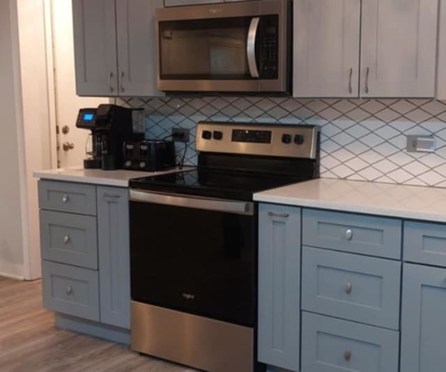 348 Niagara St, Park Forest, IL 60466 - kitchen with appliances with stainless steel finishes, gray cabinetry, light countertops, decorative backsplash, and light wood finished floors