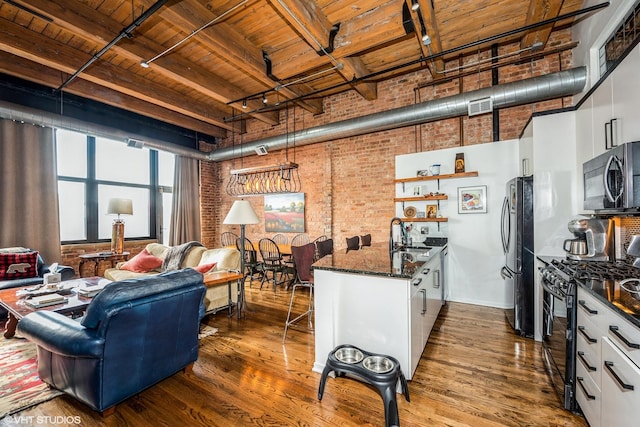 1243 S Wabash Ave Unit 302, Chicago, IL 60605 - living room featuring brick wall, wood ceiling with exposed beams, dark wood-style flooring, rail lighting, and a high ceiling