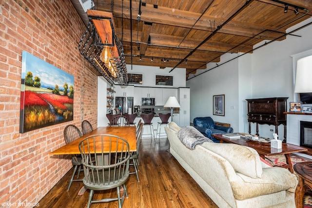 1243 S Wabash Ave Unit 302, Chicago, IL 60605 - living area featuring dark wood-style floors, a high ceiling, wood ceiling with exposed beams, brick wall, and track lighting